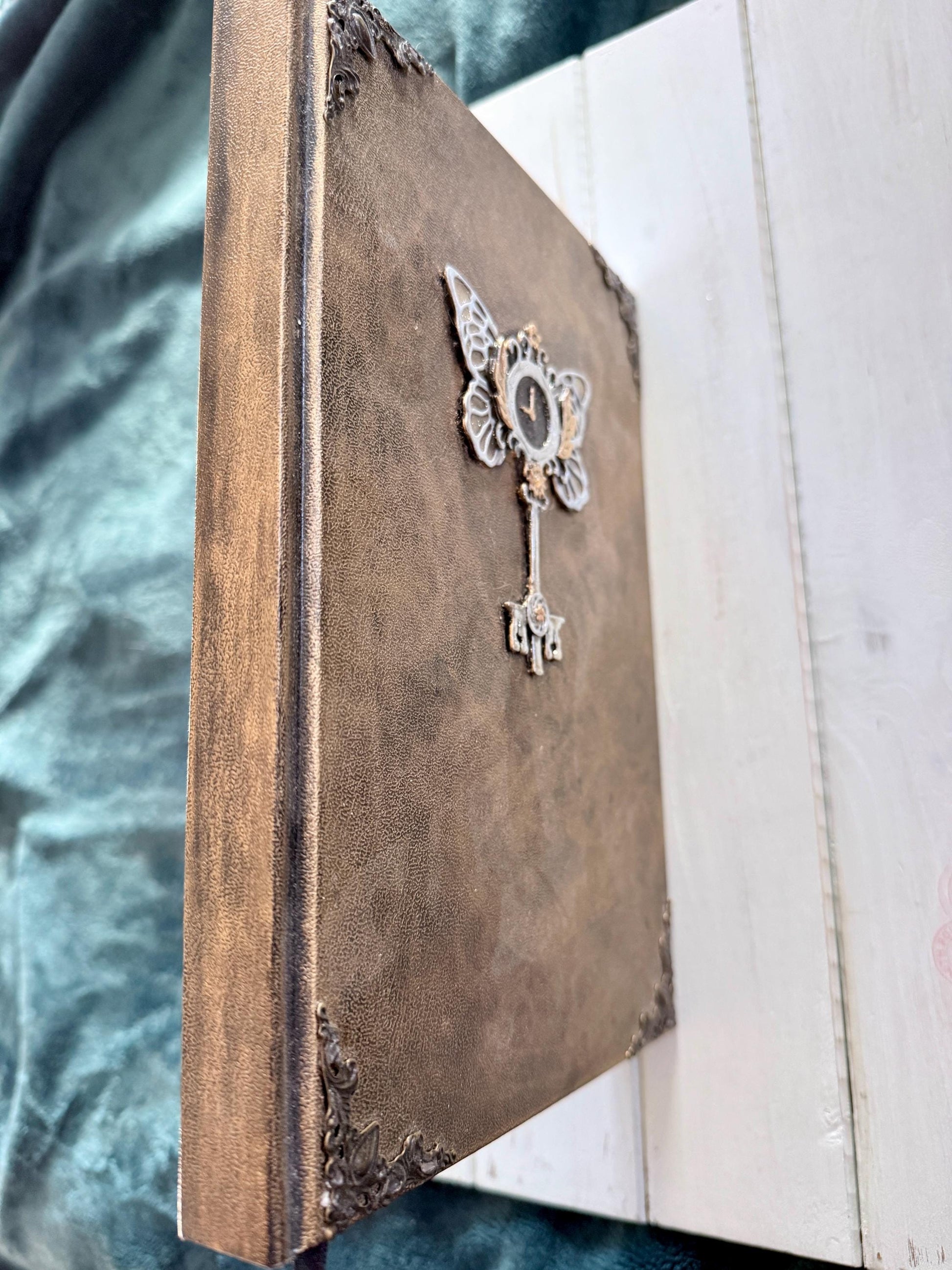A decorative Heart Key embellishment is coated in clear resin on a hardcover journal measuring 10”x7.5”x1”