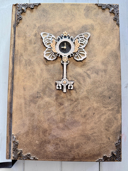 A decorative Heart Key embellishment is coated in clear resin on a hardcover journal measuring 10”x7.5”x1”