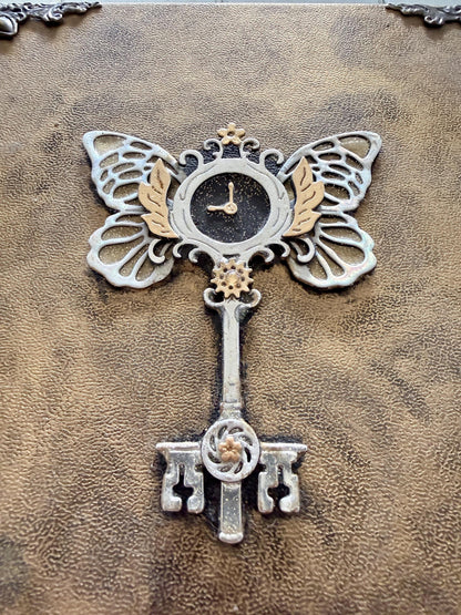 A decorative Heart Key embellishment is coated in clear resin on a hardcover journal measuring 10”x7.5”x1”